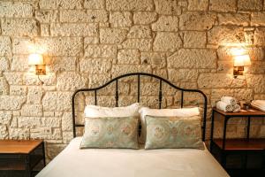 a bed with two pillows in front of a stone wall at Nill's Stone House otel in Çeşme