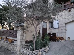 a stone house with a tree in front of it at Les Lauriers Roses in Salavas