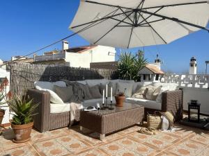 un patio con 2 sofás y una sombrilla en Holiday Apartment Casa Granaas, en Mijas