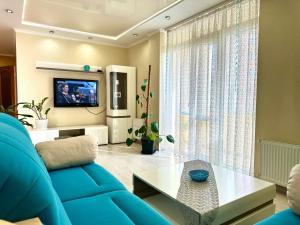 uma sala de estar com um sofá azul e uma televisão em Lux apartments in the city center, near the park and Zlata Plaza em Rivne
