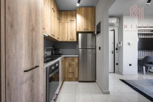 a kitchen with wooden cabinets and a stainless steel refrigerator at Green Tulip, Nilie Hospitality MGMT in Thessaloniki