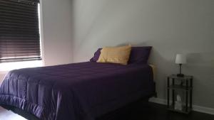 - une chambre avec un lit doté de draps violets et une fenêtre dans l'établissement Bayou Baby's Bed and Breakfast, 