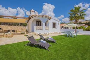 a yard with two chairs and a house at Villa Neus - PlusHolidays in Calpe