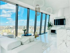 een woonkamer met een witte bank en kamerhoge ramen bij Apartament White Sky 20 Hanza Tower- Free parking in Szczecin