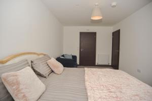 ein Schlafzimmer mit einem Bett mit Kissen und einem Stuhl in der Unterkunft Seaview Point, Superb 2- bedroom flat, 12th Floor in Southend-on-Sea