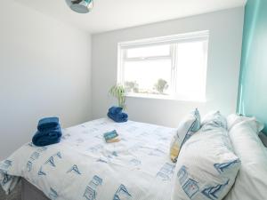 a bedroom with a bed with blue sheets and a window at Lagoon View in Weymouth