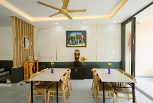 two tables in a dining room with a ceiling fan at Windbell Villa Hoi An in Hoi An
