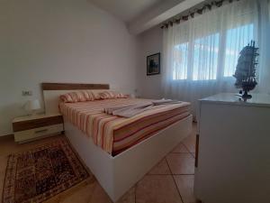 a bedroom with a large bed and a window at Kela Apartments in Sarandë