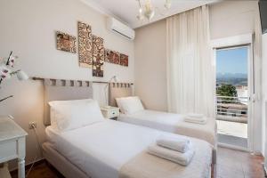 a white bedroom with two beds and a window at Diotima - Astonishing seaview in Chania