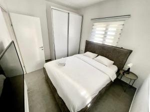 a bedroom with a white bed and a window at Apartment Beauty in Bat Yam