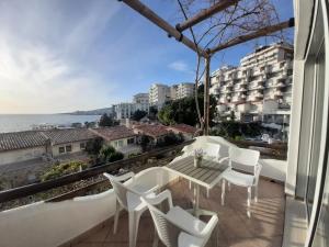 a balcony with white chairs and a table and a view at Kela Apartments in Sarandë