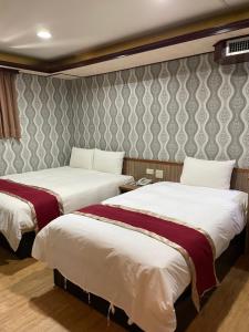 a hotel room with two beds and a wall at Mei Hua Hotel in Kaohsiung