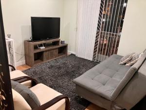 uma sala de estar com um sofá e uma televisão de ecrã plano em Duplex do Largo em Curitiba