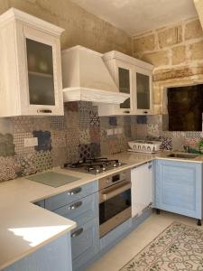 a kitchen with white cabinets and a stove top oven at Ta' Tereza in Xagħra