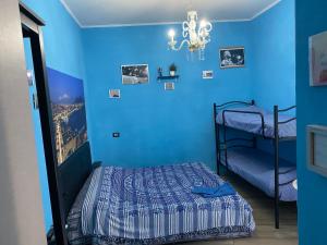 una camera da letto con pareti blu, un letto e un lampadario a braccio di Na tazzulel e cafe a Napoli