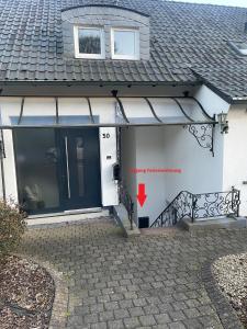 una casa blanca con una puerta azul con una flecha roja en Ferienwohnung am Hengsteysee en Herdecke