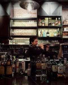a woman standing behind a bar with bottles of alcohol at Man Cave Hostel Vientiane in Ban Nongdouang