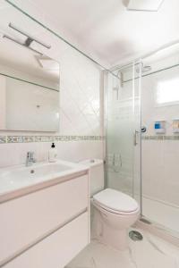 a white bathroom with a toilet and a shower at Sol y Mar Puerto Paraiso in Puerto Rico de Gran Canaria