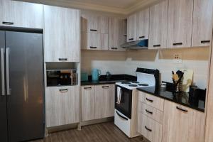 a kitchen with wooden cabinets and a stainless steel refrigerator at Katonga Lolani Apartment in Lusaka