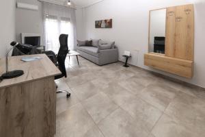 an office with a desk and a chair and a couch at Stay Here - Διαμέρισμα στο κέντρο του Βόλου in Volos