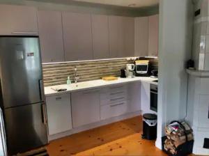 La cuisine est équipée de placards blancs et d'un réfrigérateur en acier inoxydable. dans l'établissement Villa Vilu, à Naantali