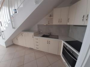 a kitchen with white cabinets and a staircase at Kela Apartment 3 in Sarandë