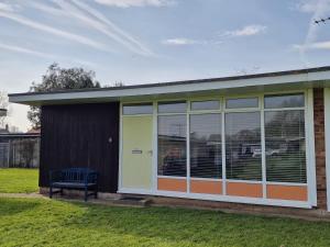 a screened in porch of a house with a bench at 170 Broadside Holiday Chalet near Broads & Beaches in Stalham