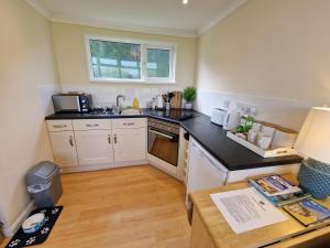 a small kitchen with white cabinets and a table at 170 Broadside Holiday Chalet near Broads & Beaches in Stalham