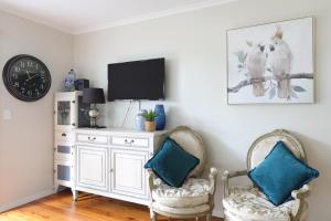 a living room with two chairs and a tv at Camellia Cottage in Wentworth Falls