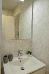 uma casa de banho com um lavatório branco e um espelho. em Calle Abades Centro de Sevilla em Sevilha