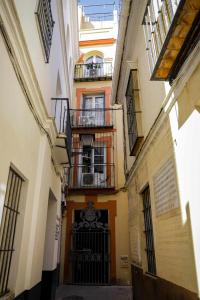 um beco com edifícios, uma porta e uma varanda em Calle Abades Centro de Sevilla em Sevilha