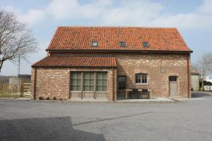 un edificio de ladrillo con techo rojo en una calle en De Landweg, en Tielt