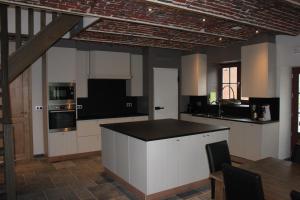 una cucina con armadi bianchi e piano di lavoro nero di De Landweg a Tielt