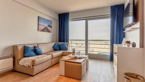 ein Wohnzimmer mit Couch und großem Fenster in der Unterkunft Holiday Suites Blankenberge in Blankenberge