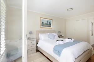 a white bedroom with a bed and a shower at Camellia Cottage in Wentworth Falls