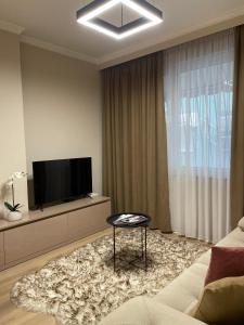 a living room with a flat screen tv and a table at Honey Suite in Tirana