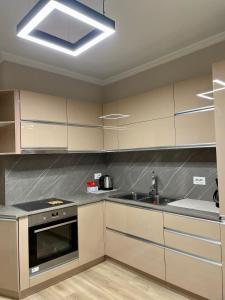 una cocina con armarios blancos y fregadero en Honey Suite, en Tirana
