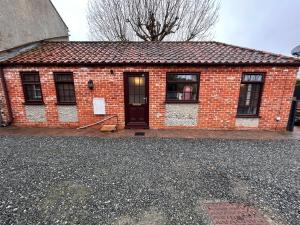 a red brick building with a door and windows at The Old Stables in Mews in Kessingland