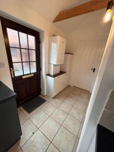 an empty kitchen with a door and a refrigerator at The Old Stables in Mews in Kessingland