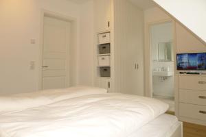 a white bedroom with a bed and a television at Aurelia Haus 1 in Wyk auf Föhr +6 photos