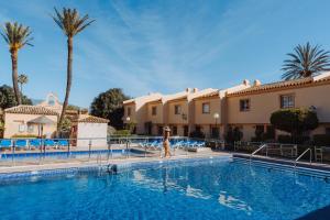a woman walking by a swimming pool in a resort at Ramada Hotel & Suites by Wyndham Costa del Sol in Fuengirola