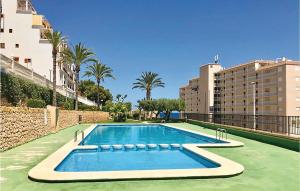 サンタ・ポラにあるBeautiful Apartment In Santa Pola With Outdoor Swimming Poolのヤシの木や建物のある大型スイミングプール