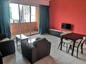 a living room with a couch and a table with a television at Globallon Services Apartment, Melaka Town Hotel in Malacca