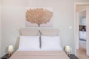 a bed with white pillows and a tree picture on the wall at Tenniside view in Ágios Rókkos