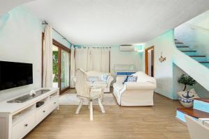 sala de estar con sofá, silla y TV en A due passi da mare en Abbiadori