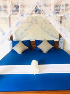 a blue and white bed with blue and white pillows at SILVER RAIL in Galle
