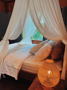 a bed with white curtains and a table with a lamp at Villa Neshama in Canggu