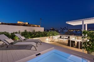 a rooftop patio with chairs and a swimming pool at night at Divani Palace Acropolis in Athens