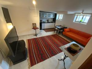 a living room with an orange couch and a television at Bethlehem-the-Wall Apartment in Bethlehem