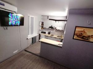 uma sala de estar com uma cozinha e uma televisão na parede em Квартира - студія em Konotop